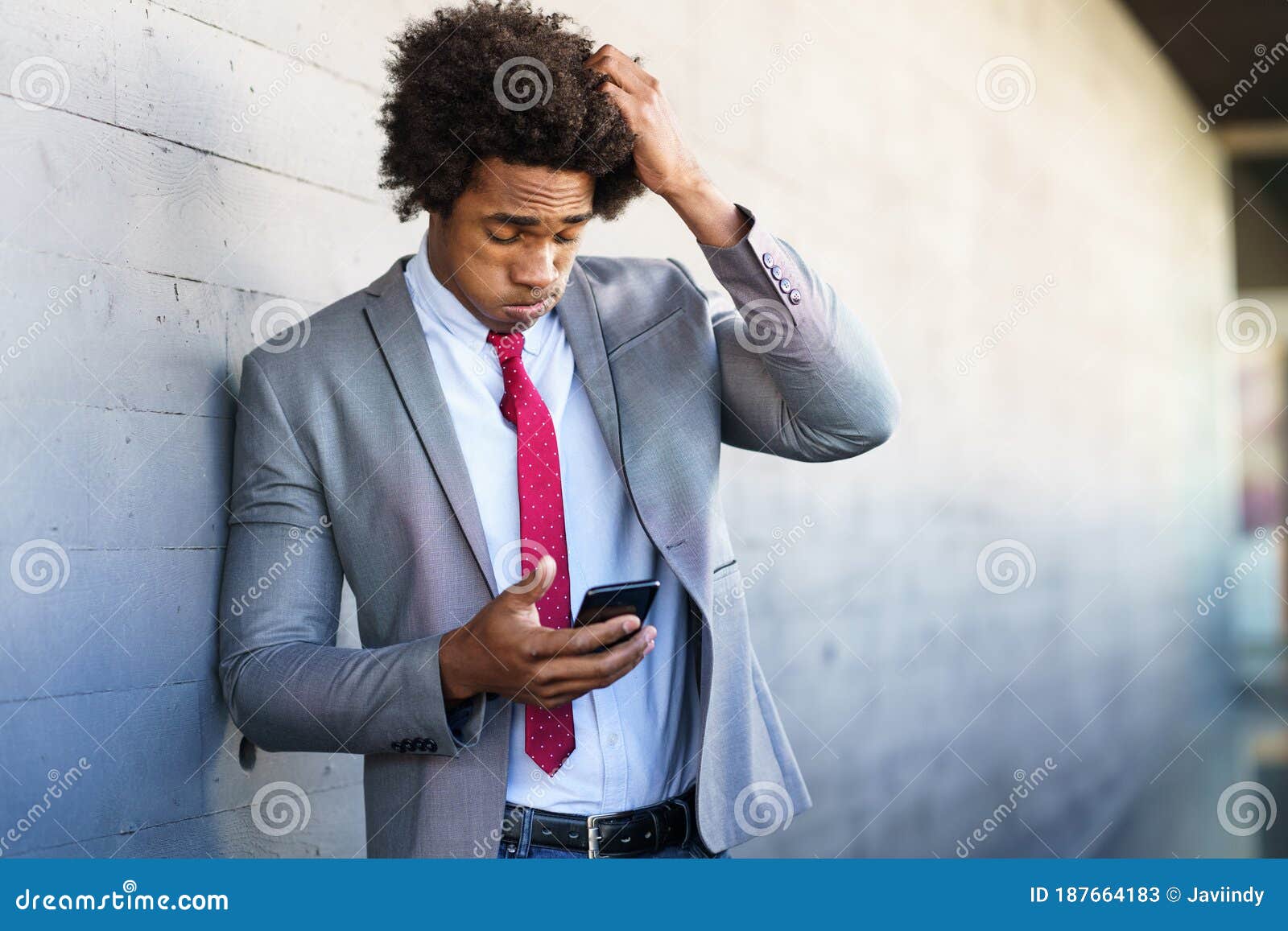 worried black businessman using his smartphone outdoors.