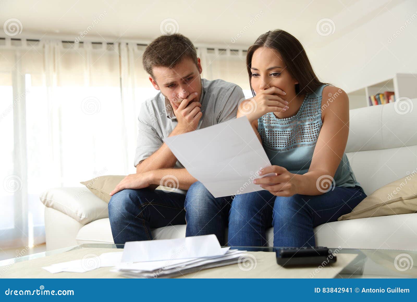 worried couple reading a letter at home