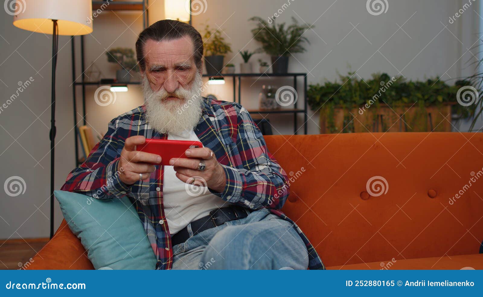 Worried Funny Senior Old Grandfather Man Playing Racing Online Video Games on Smartphone at Home Stock Image