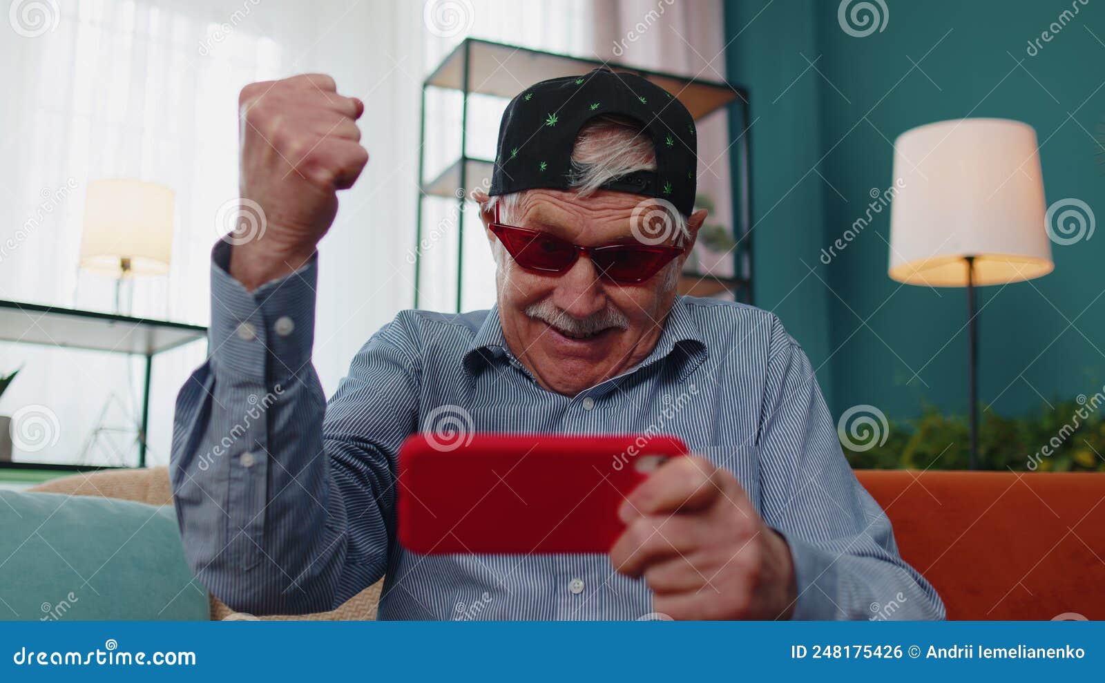 Worried Funny Senior Old Grandfather Man Playing Shooter Online Video Games on Mobile Phone at Home Stock Photo