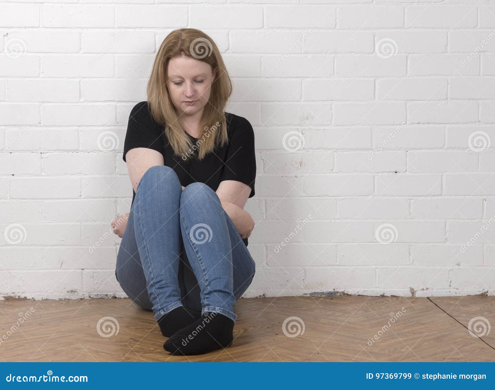Worried and Nervous Female Sitting Against a White Brick Wall Stock ...