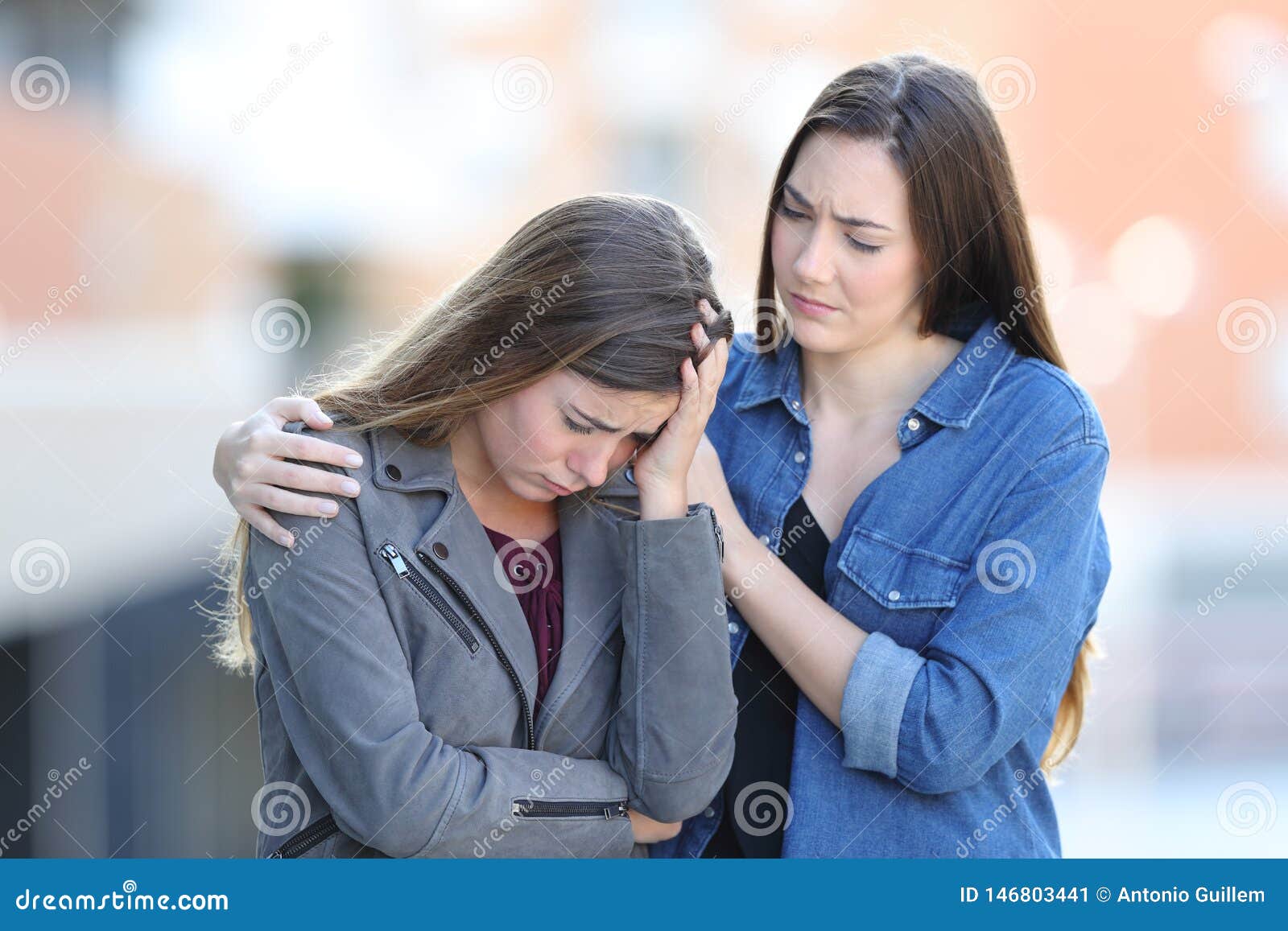 worried woman comforting her sad friend in the street