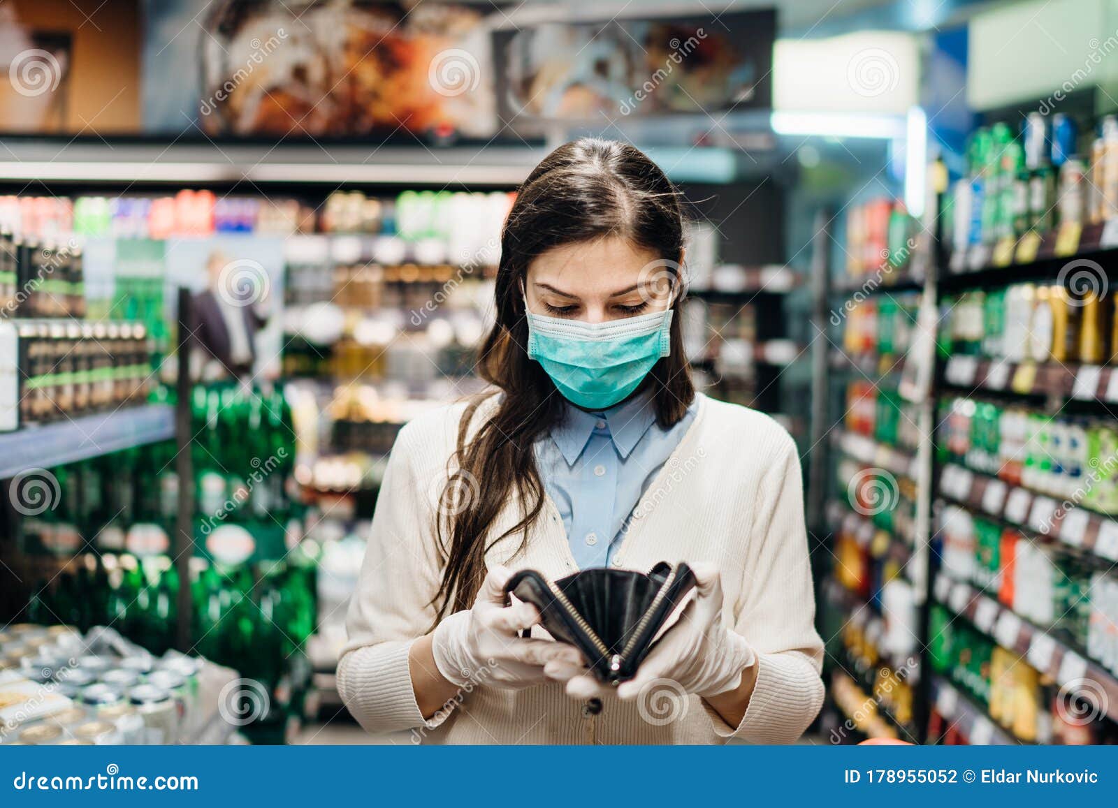 worried woman with mask groceries shopping in supermarket looking at empty wallet.not enough money to buy food.covid-19 quarantine