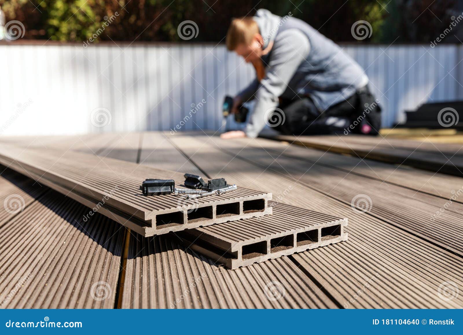 wpc terrace construction - worker installing wood plastic composite decking boards