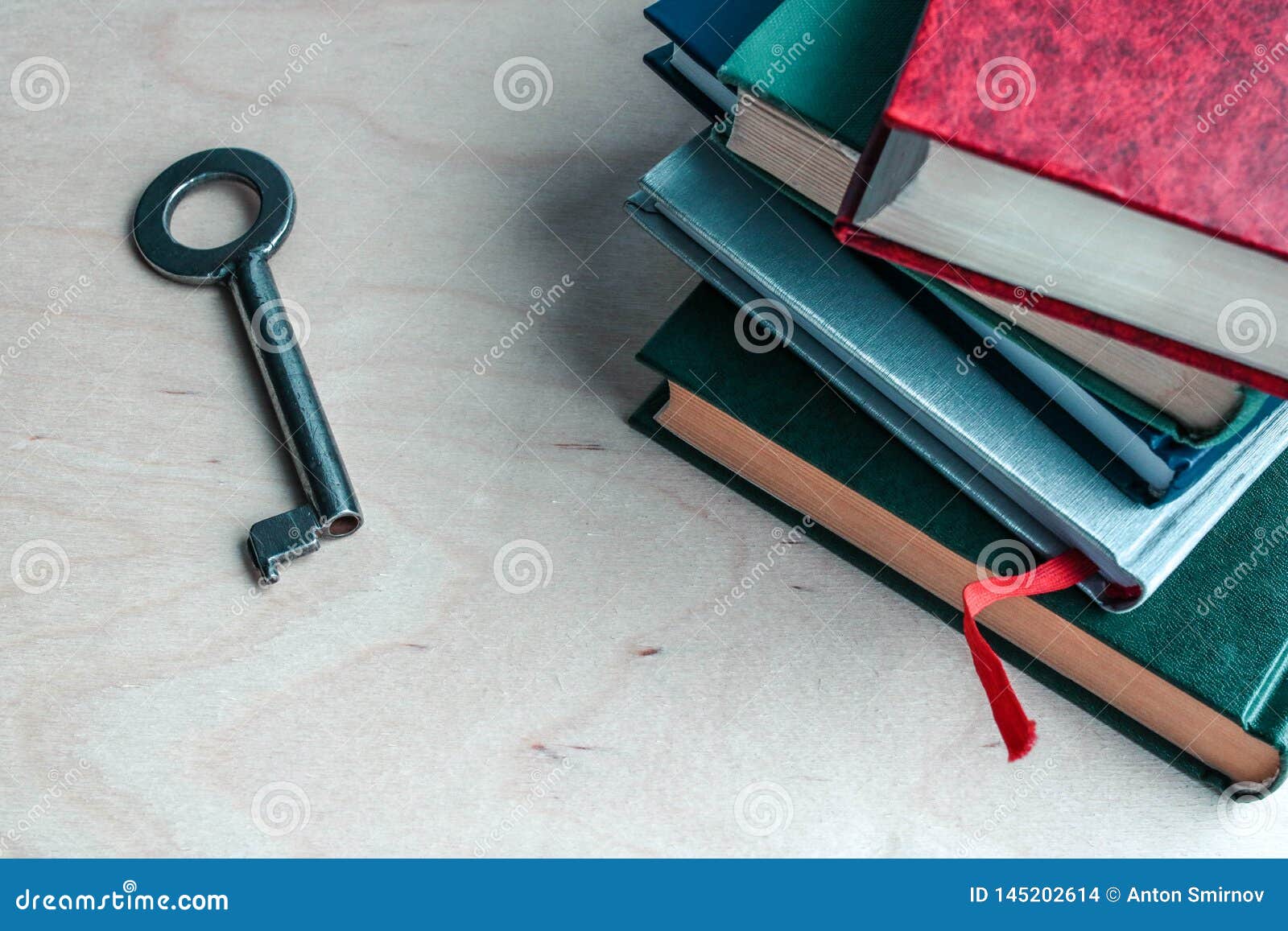 Wpisuje i sterta ksi??ki na drewnianym tle Metafora - klucz wiedza. Book reading concept is a key to success, book stack and key on vintage wooden table background. Key to knowledge