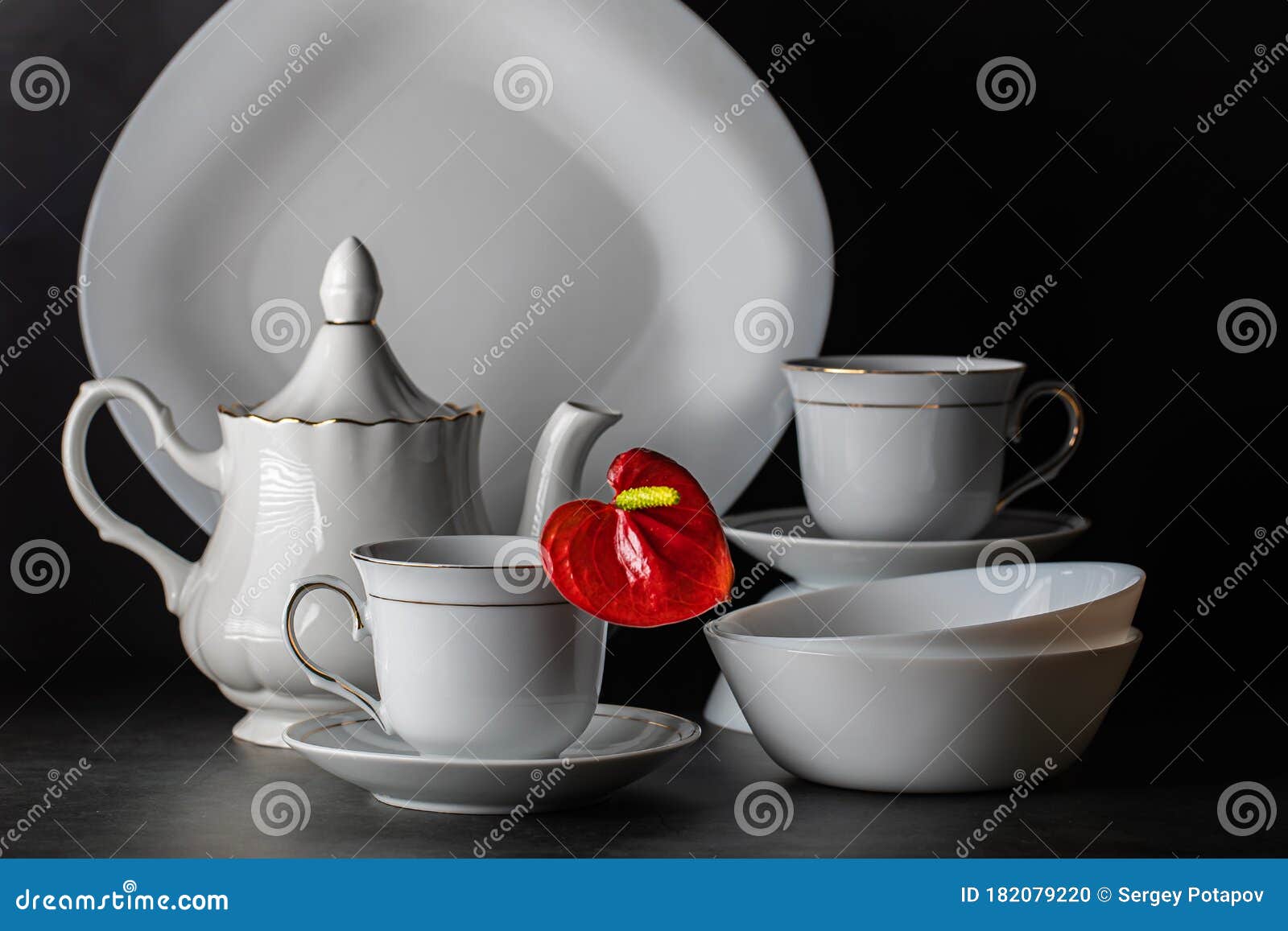 Uma mesa com um jogo de chá e um bule com xícaras de chá.