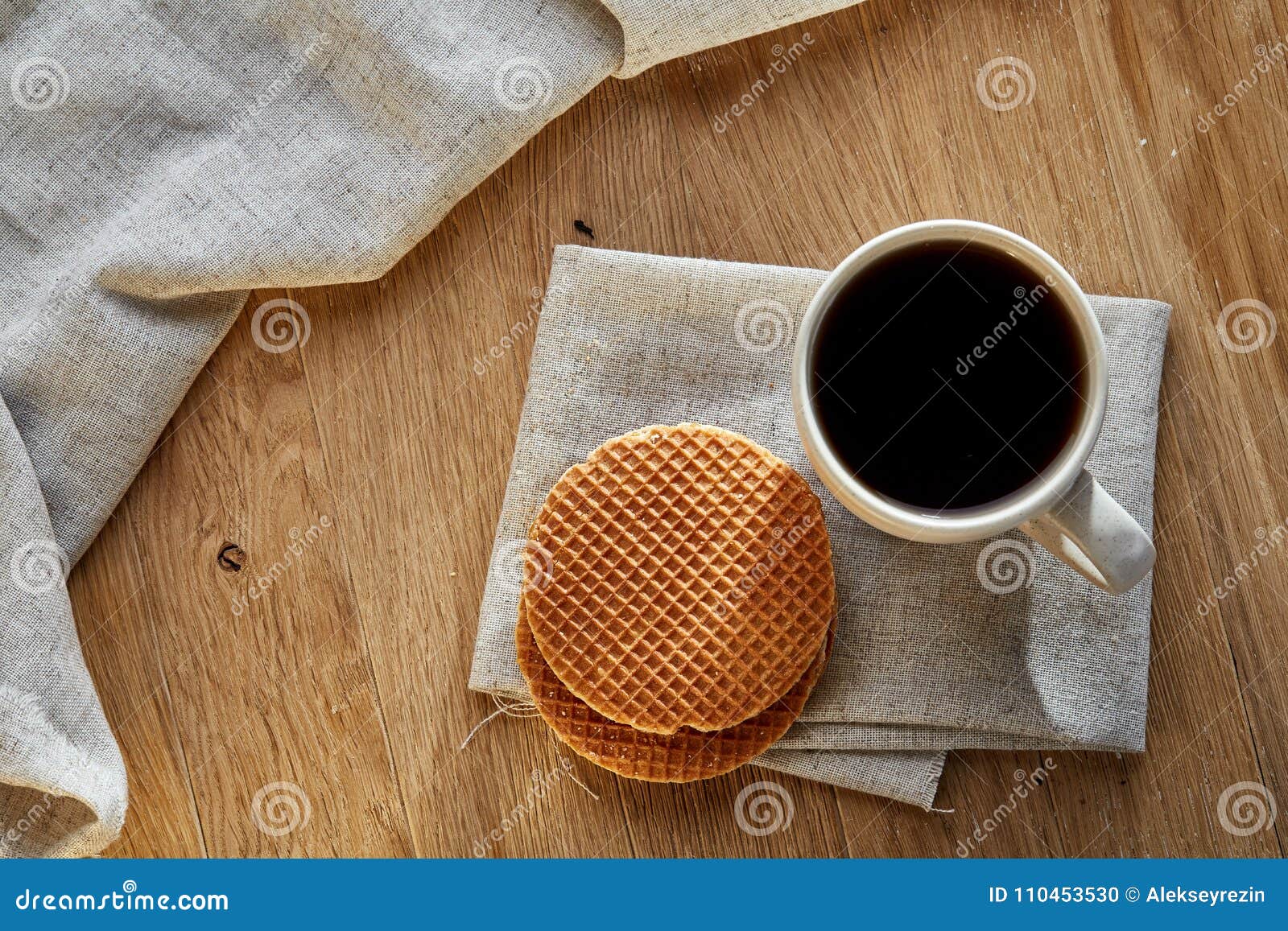 Xícara de chá da porcelana com os waffles no guardanapo em um fundo de madeira rústico, vista superior do algodão, vertical. Copo branco da porcelana do chá cinzento ou preto do conde com wafflesdecorated com o guardanapo claro em um fundo de madeira rústico, vista superior do algodão, foco seletivo, vertical