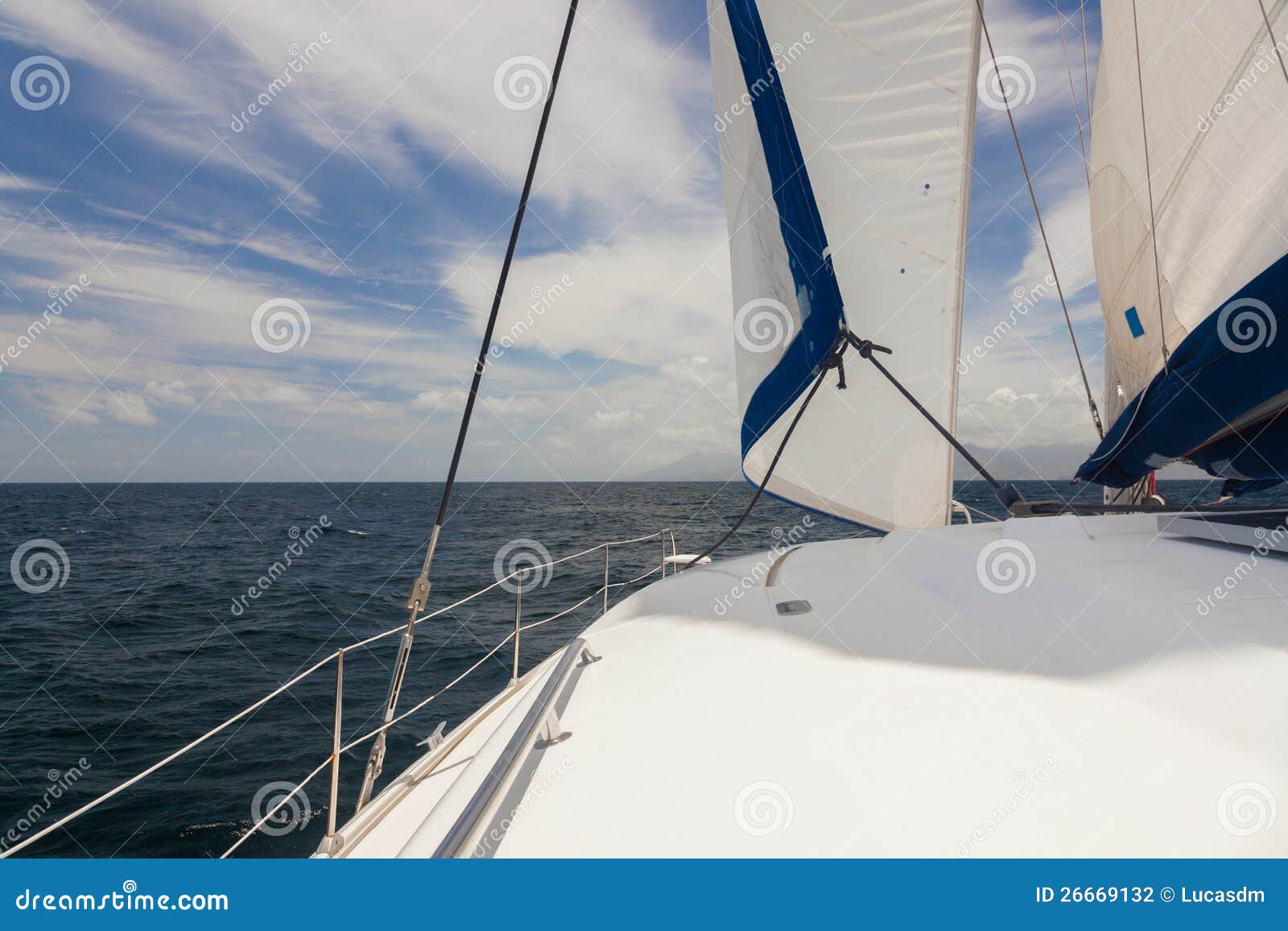 Yate en el océano abierto. Pieza del yate blanco con la vela en el océano abierto. Nadie. Cielo azul nublado.