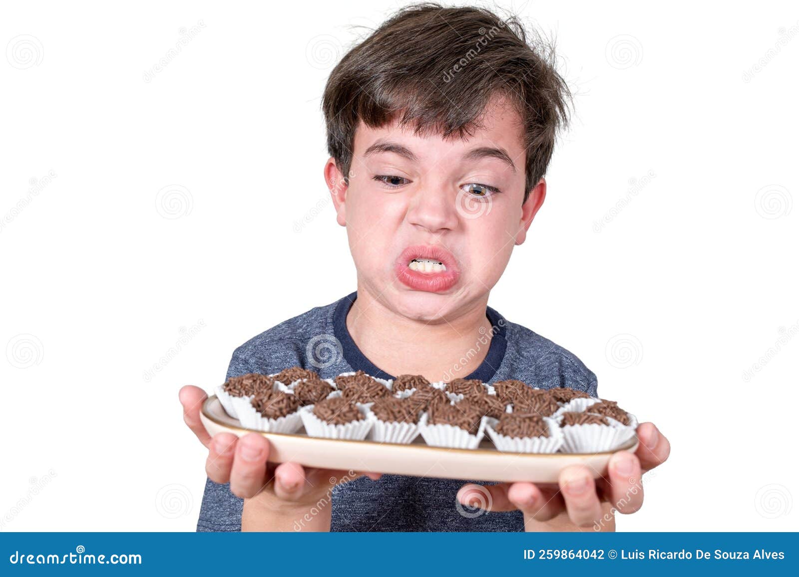 9 Year Old Brazilian Holding A Tray With Several Brazilian Fudge Balls And Making An Angry Face