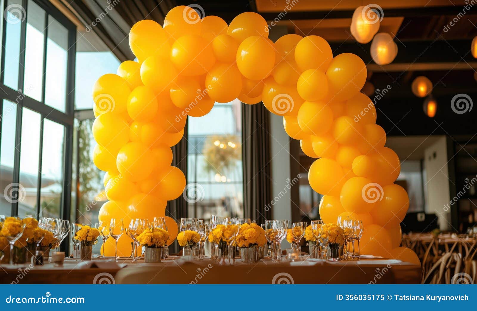 yellow balloon arch decorates elegant dining setup with flowers and glassware