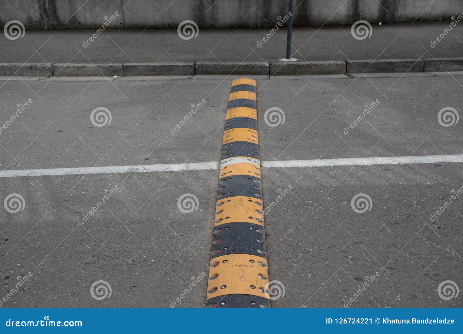 Yellow And Black Striped Speed Bump On An Asphalt Road Stock Image