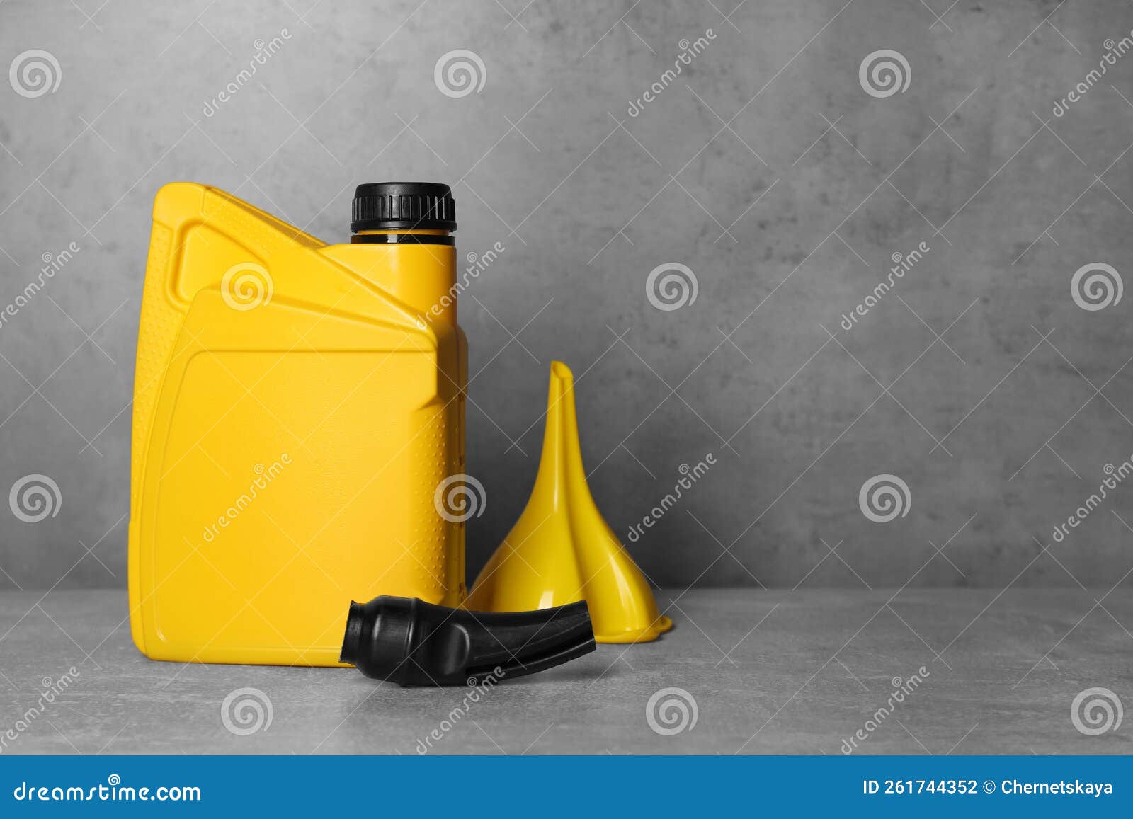 Yellow Canister with Motor Oil and Plastic Funnel on Light Grey Table