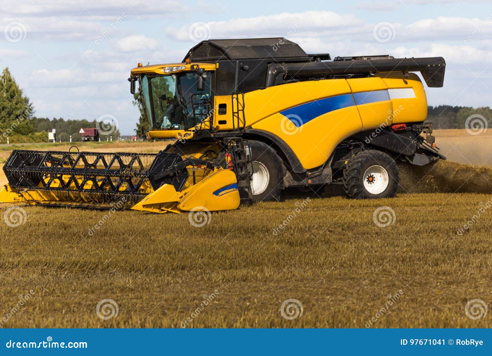 yellow combine harvester on a wheat field with blue sky