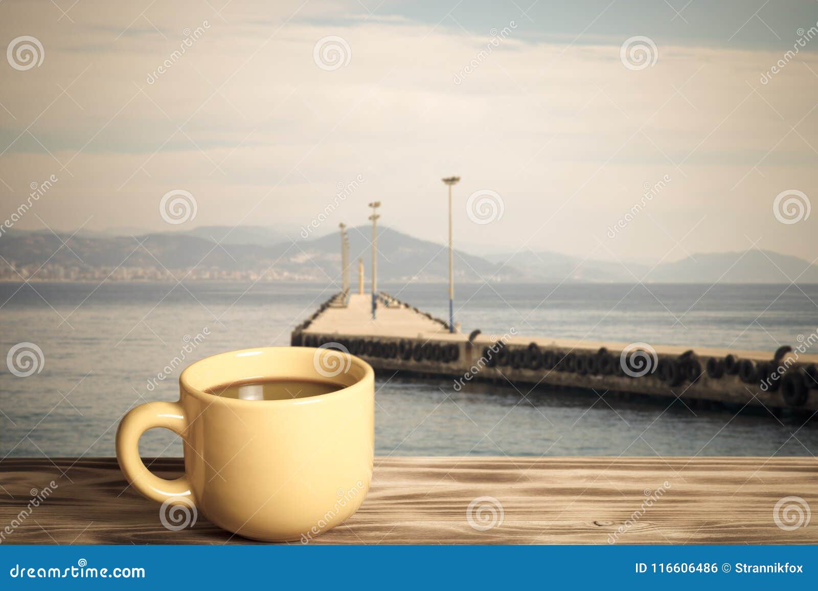 yellow cup with tea on wooden table opposite a defocused backgr