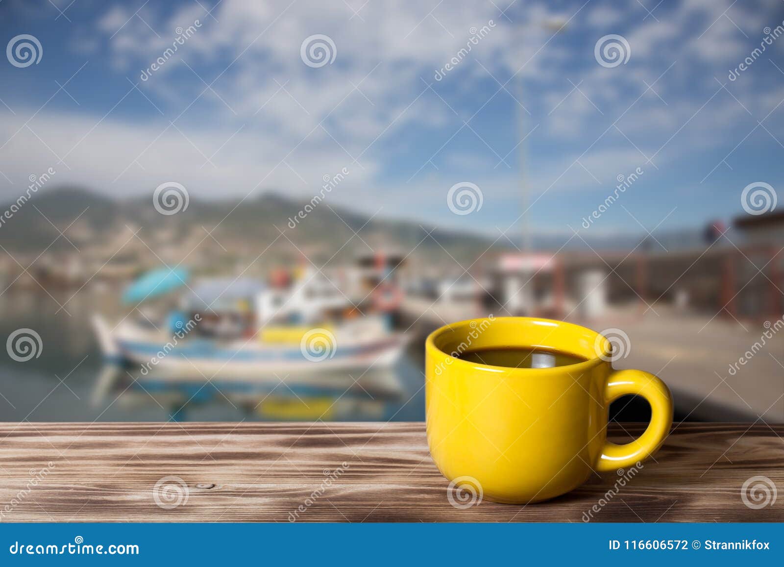 yellow cup with tea on wooden table opposite a defocused backgr