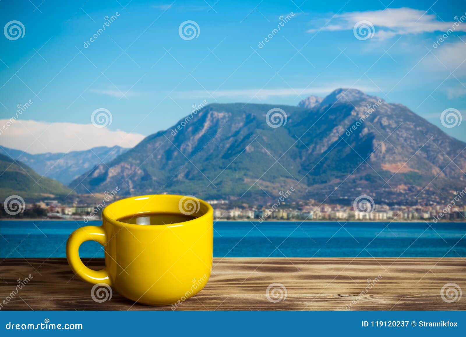yellow cup with tea on wooden table opposite a defocused backgr