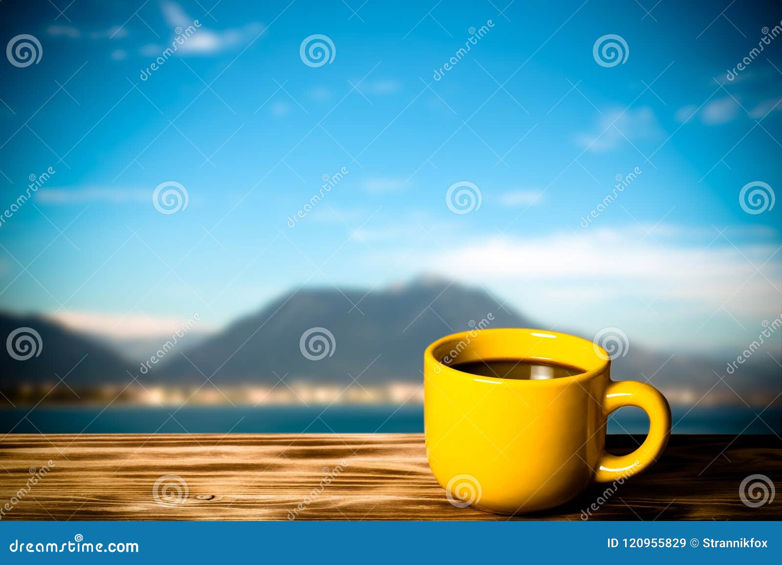 yellow cup with tea on wooden table opposite a defocused backgr