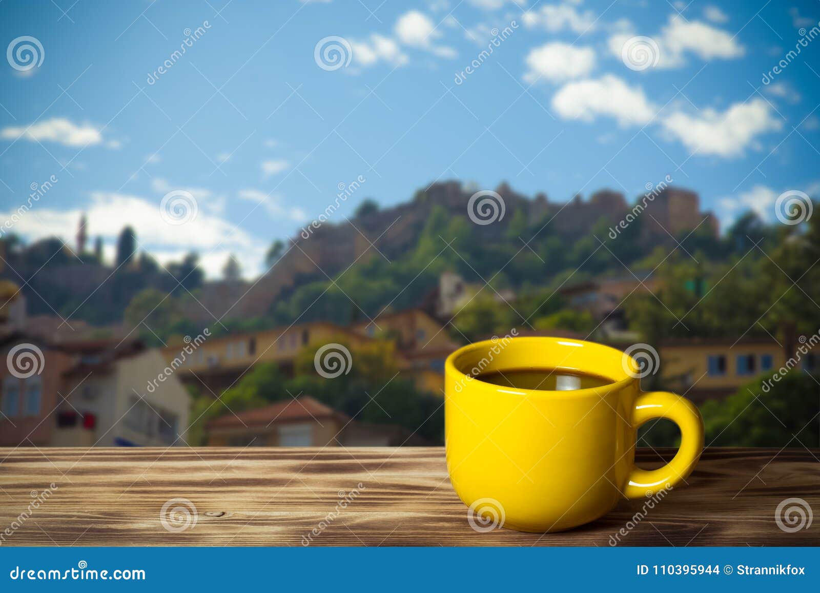 yellow cup with tea on wooden table opposite a defocused backgr