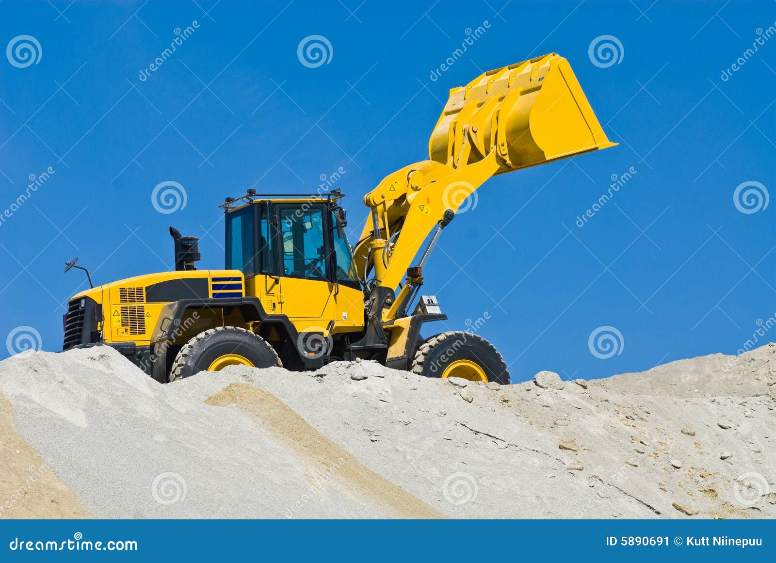 A yellow excavator working on sand, blue sky in the background.
