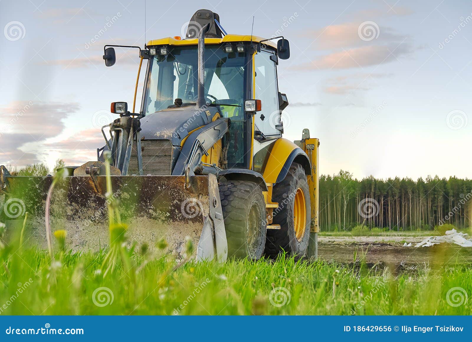 yellow excavator. yellow tractor on the field. construction machinery on field. large yellow wheel loader aligns a piece