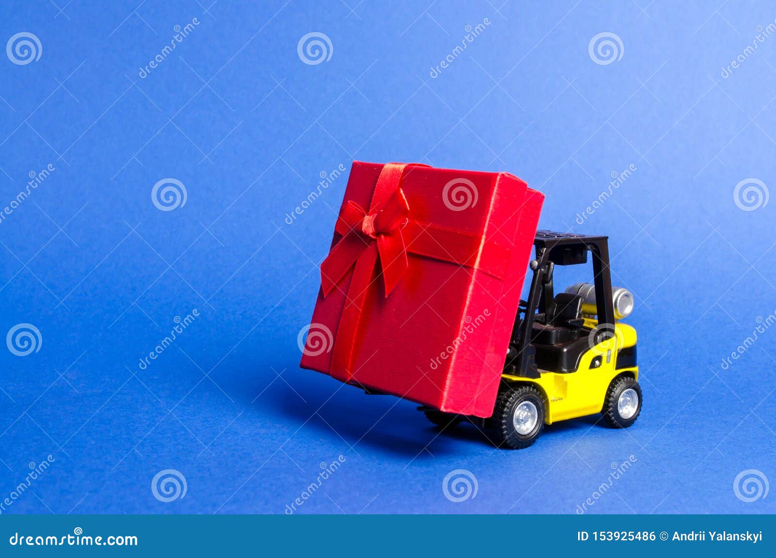 yellow forklift truck carries a red gift box with a bow. purchase and delivery of a present. retail, discounts and contests.