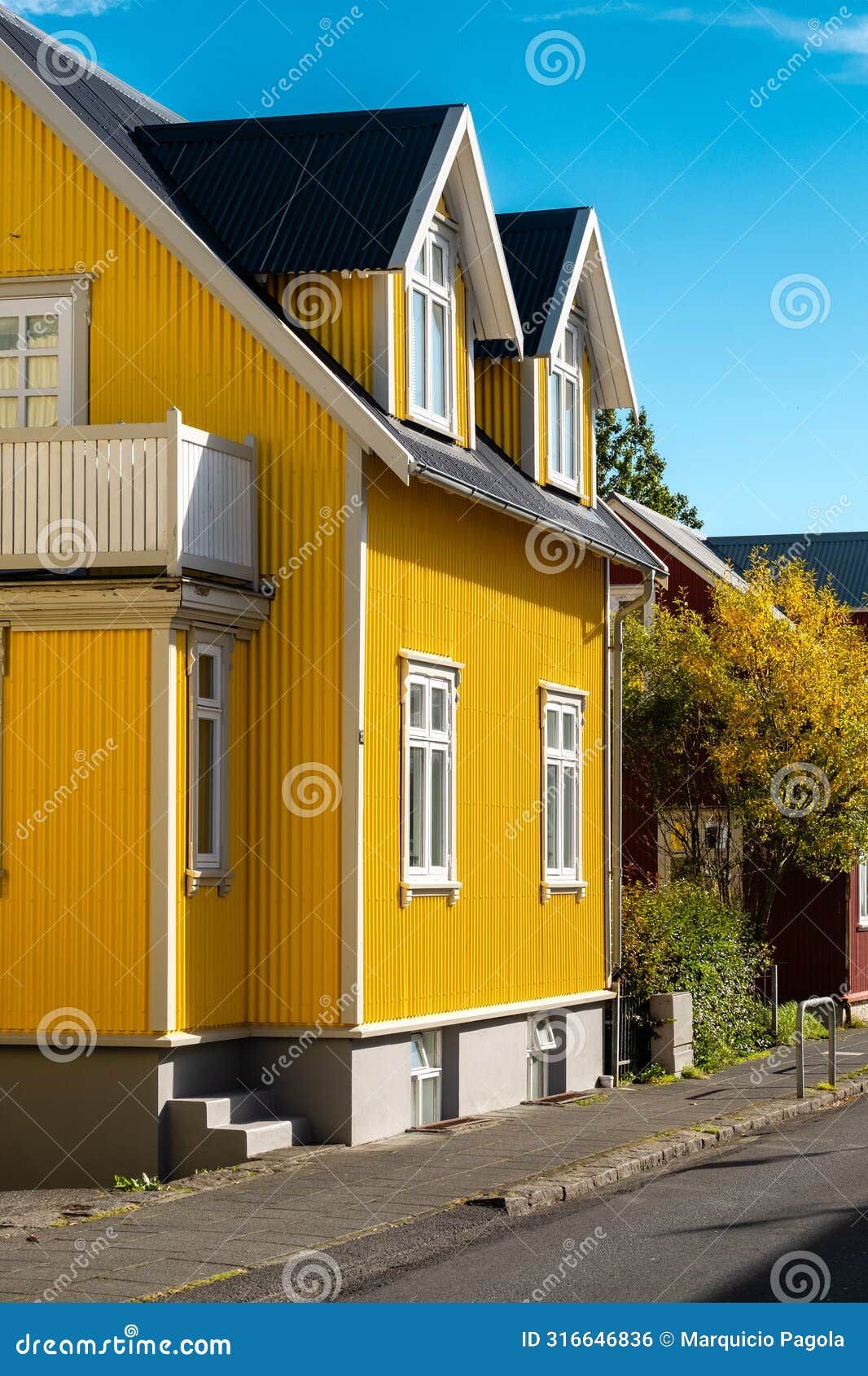 a yellow house with a black roof and white trim