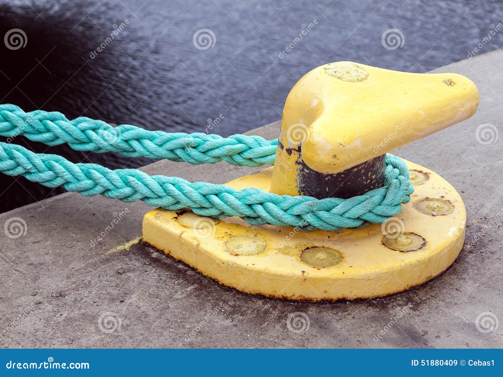 yellow mooring bollard with green ropes