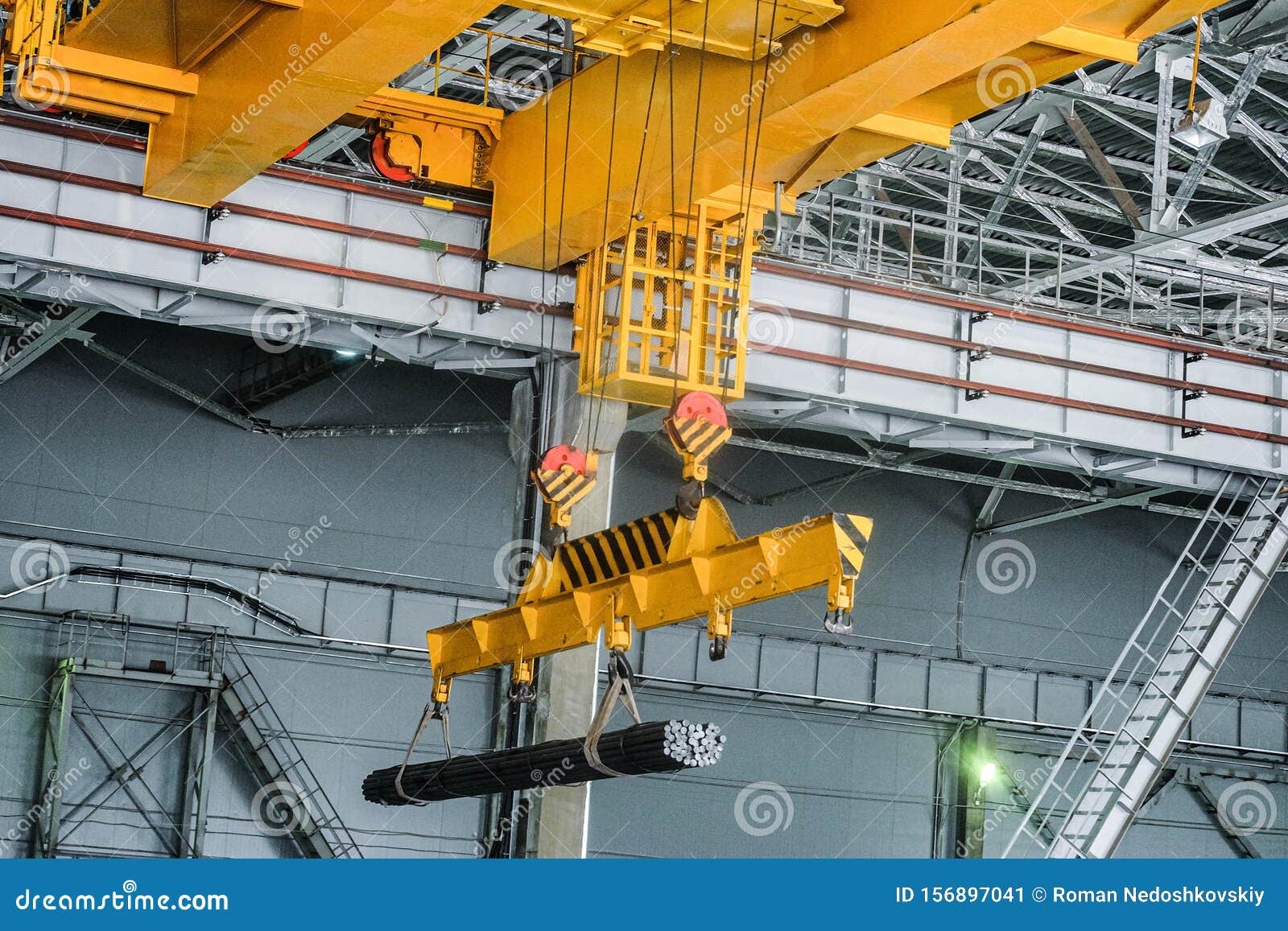yellow overhead crane carries cargo in engineering plant shop