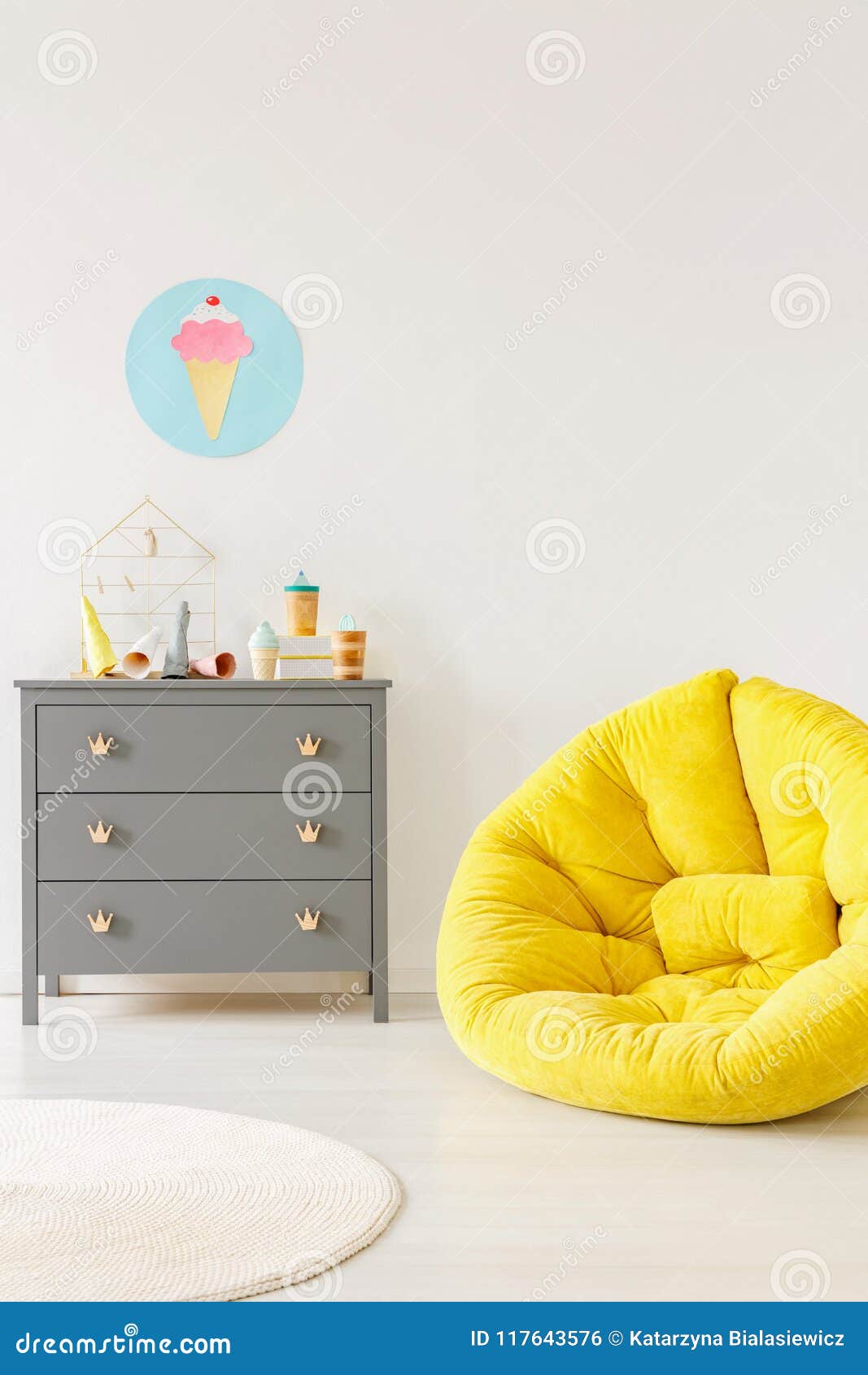 Yellow Pouf Next To A Grey Chest Of Drawers And Ice Cream Poster