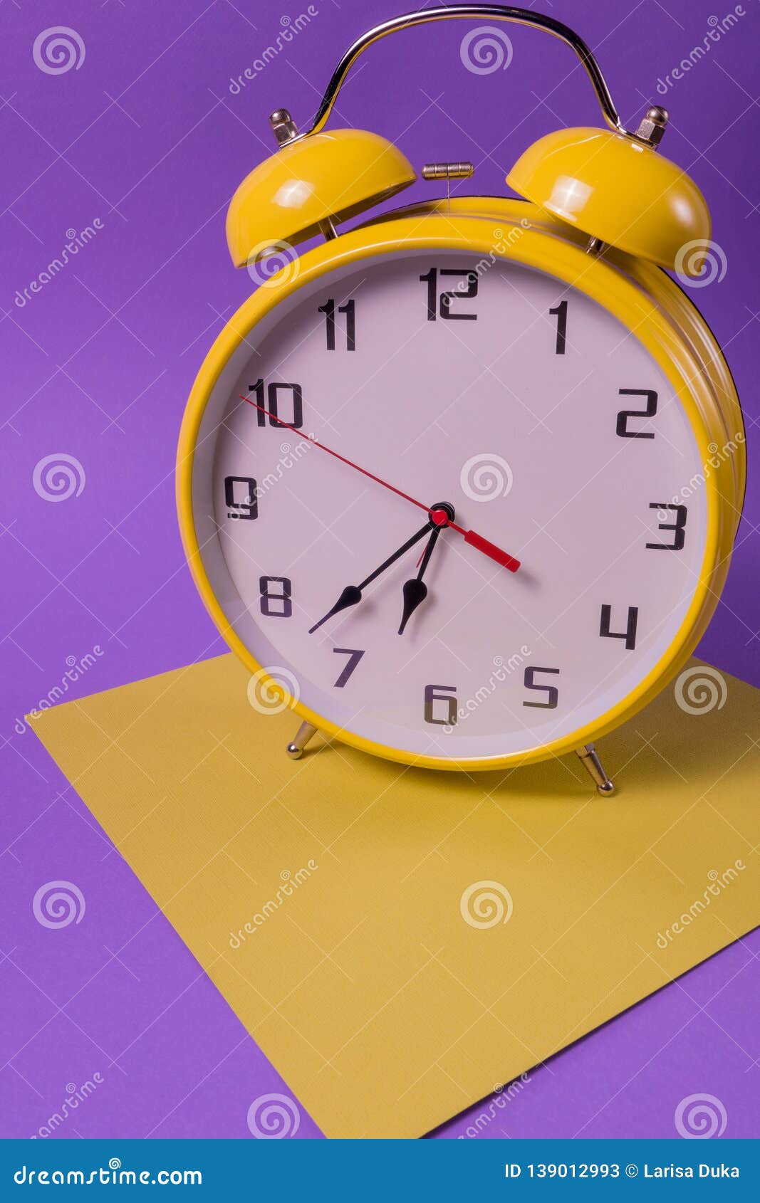 yellow retro style alarm clock with twenty two minutes to seven o`clock