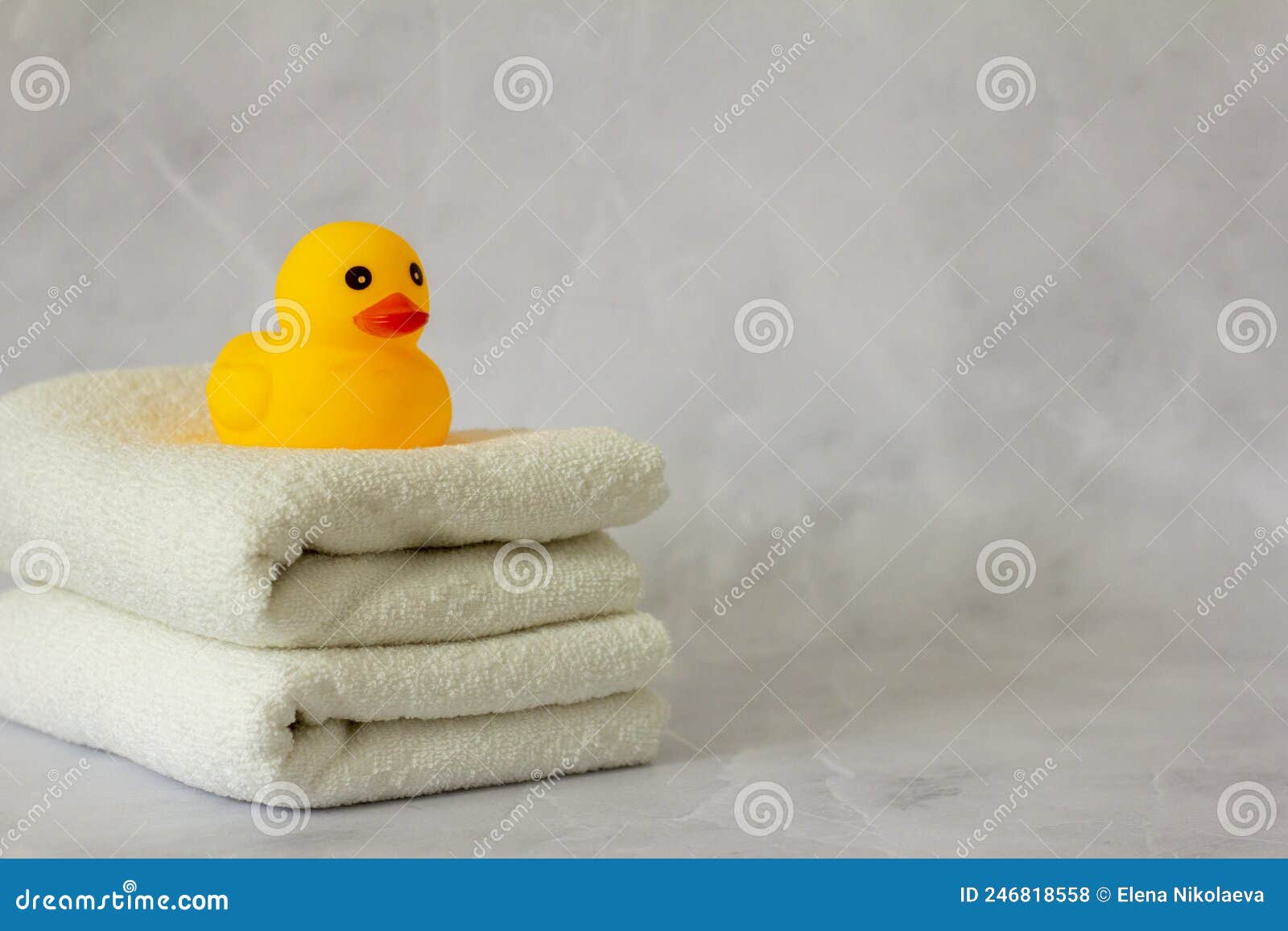A Yellow Rubber Duck for Bathing on a Stack of Clean White Towels Stock