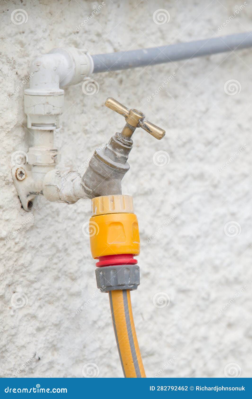 Yellow Rubber Hose and Wall Mounted Holder Outdoors Stock Photo Image