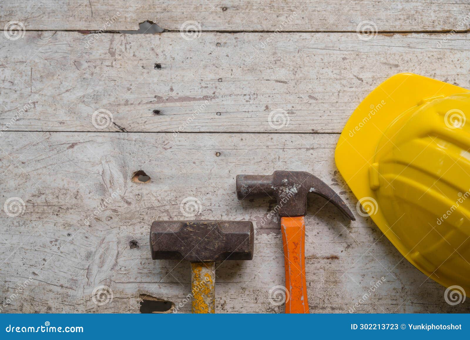 yellow safety helmet and rolled up architectural blueprints on a wooden desk