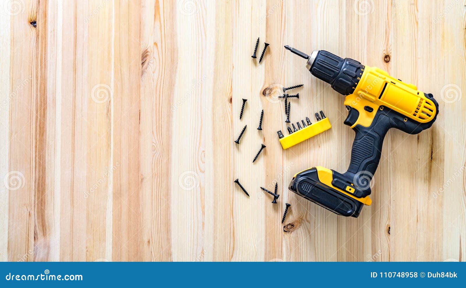 Yellow Screwdriver on a Wooden Table, Screws, a Set of Bits. Stock