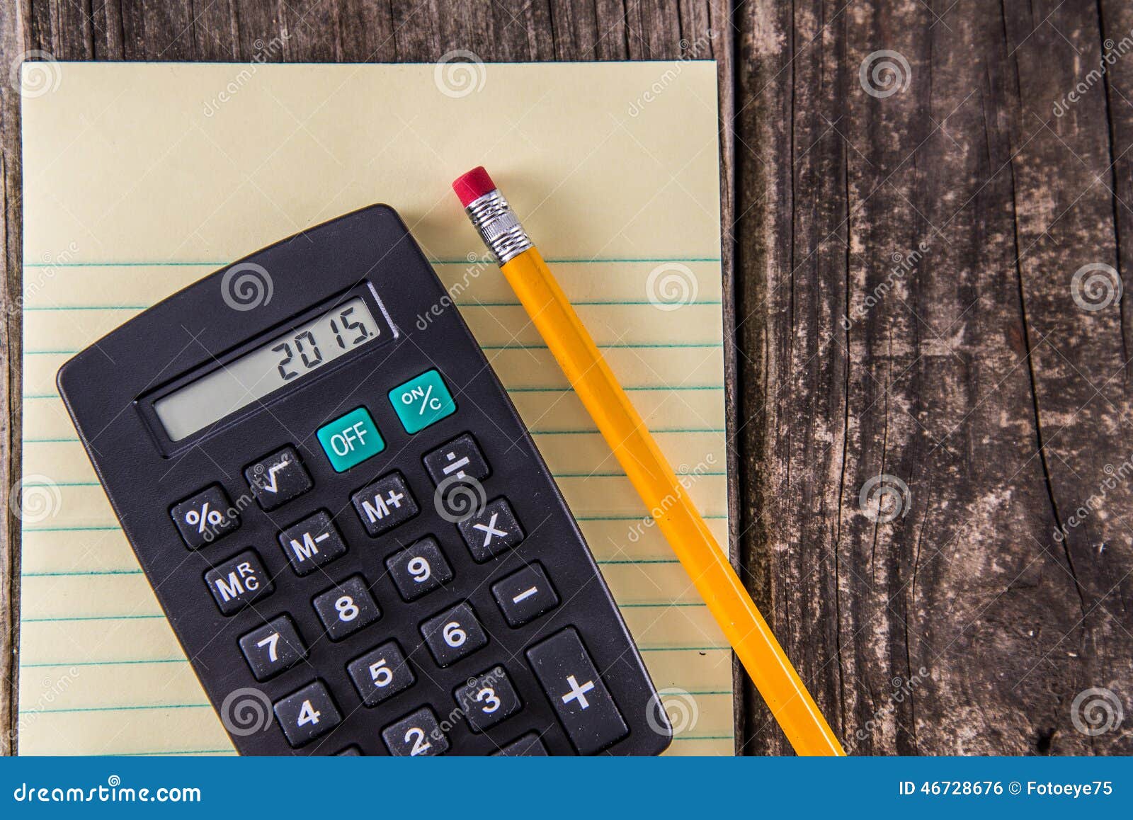 Yellow Tablet Pencil &amp; Calculator on Vintage Desk. Yellow Tablet with lines, calculator and yellow pencil laying on old vintage wood desk background - year 2015 on the LCD - concept for 2015 tax return filing / accounting