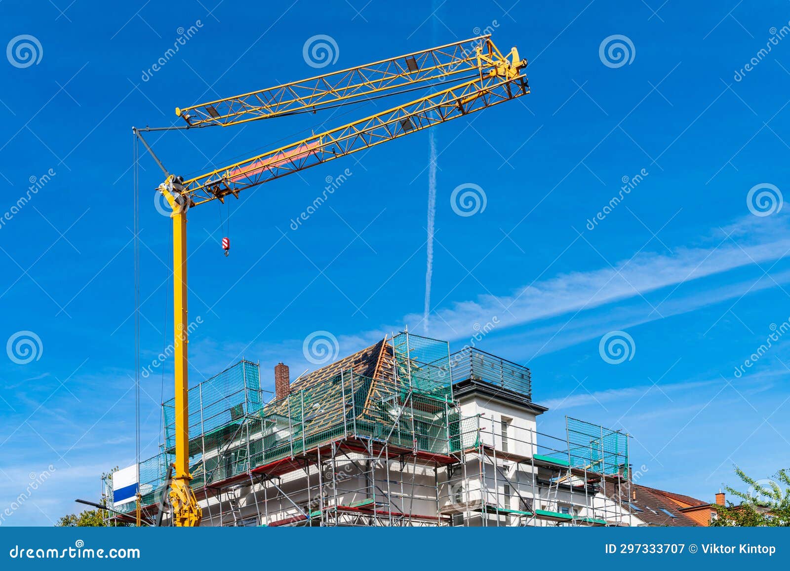 Yellow Tower Crane Over a House Under Construction Surrounded by