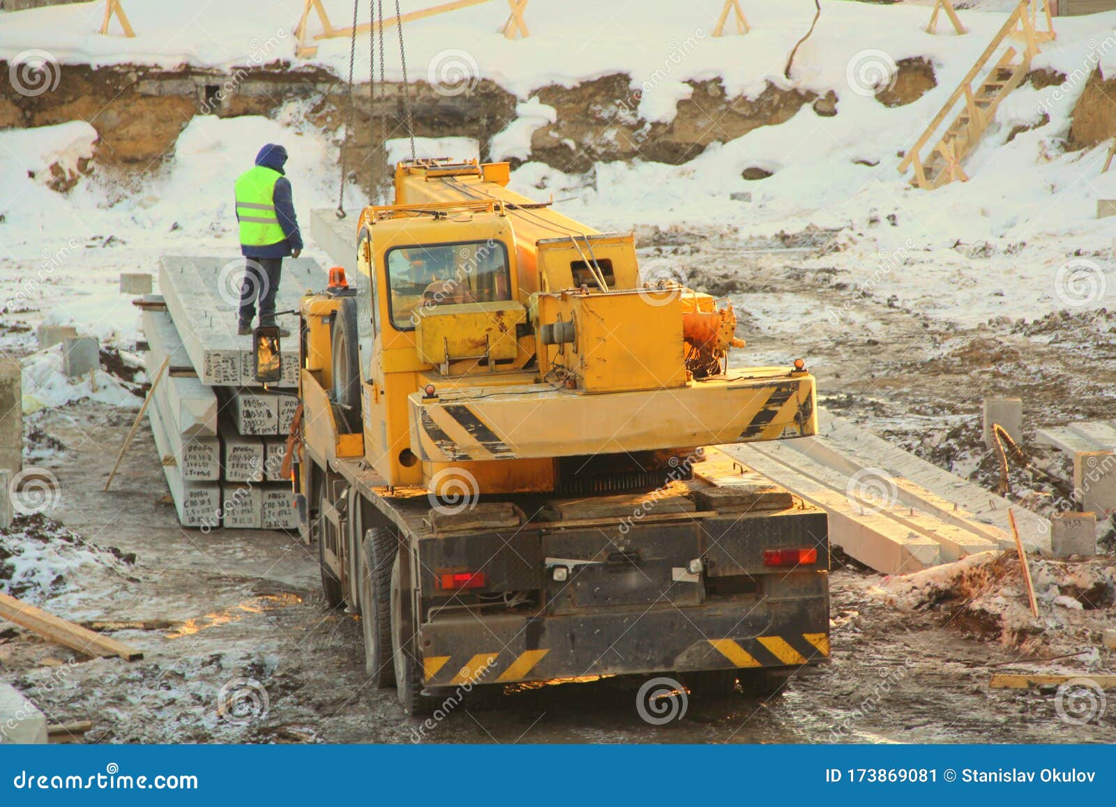 yellow truck-mounted truck mounted crane at a construction site in winter amid snow in russia