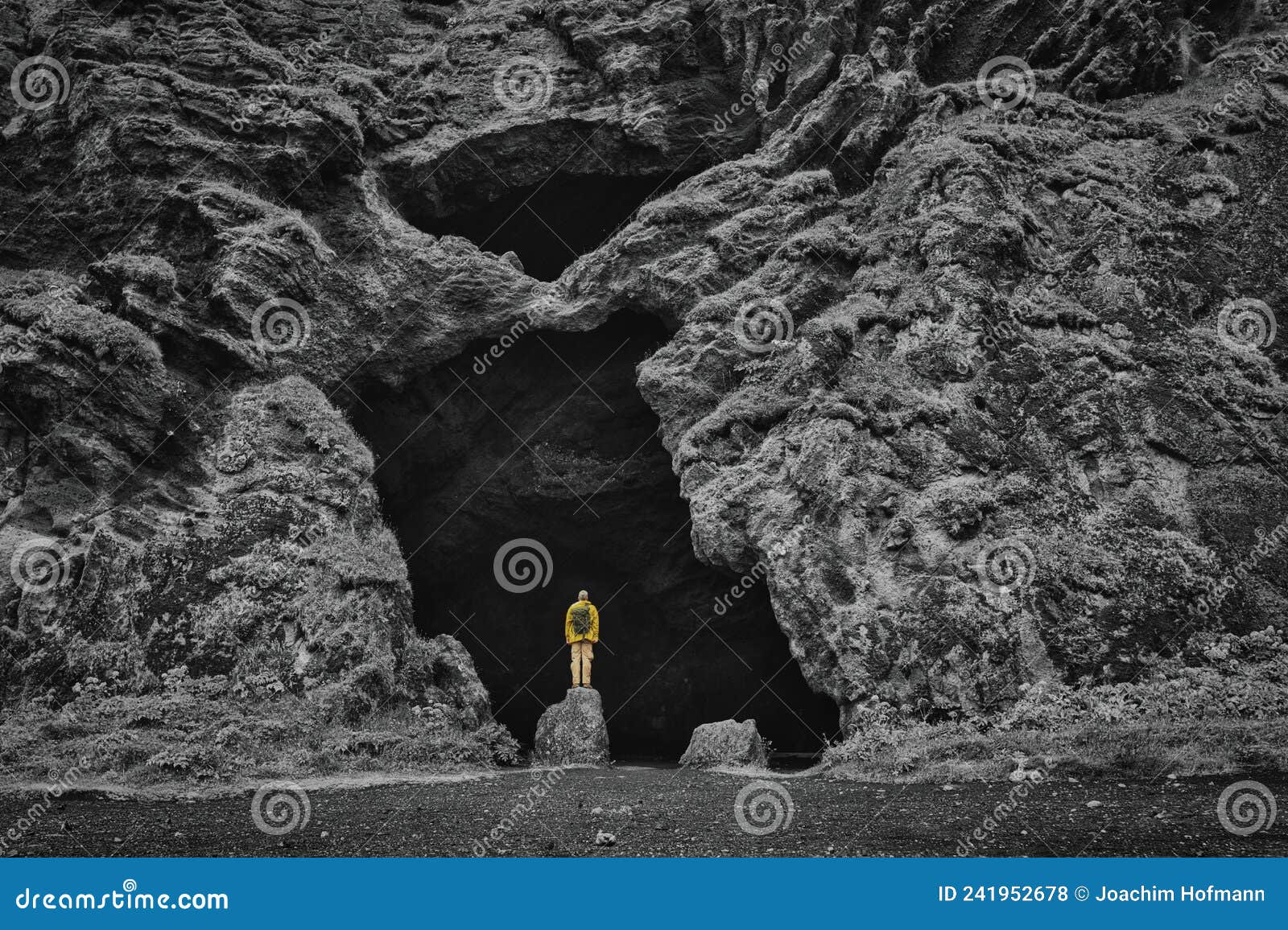 yoda cave at hjorleifshofdi in iceland, black and white, adventurer with yellow raincoat