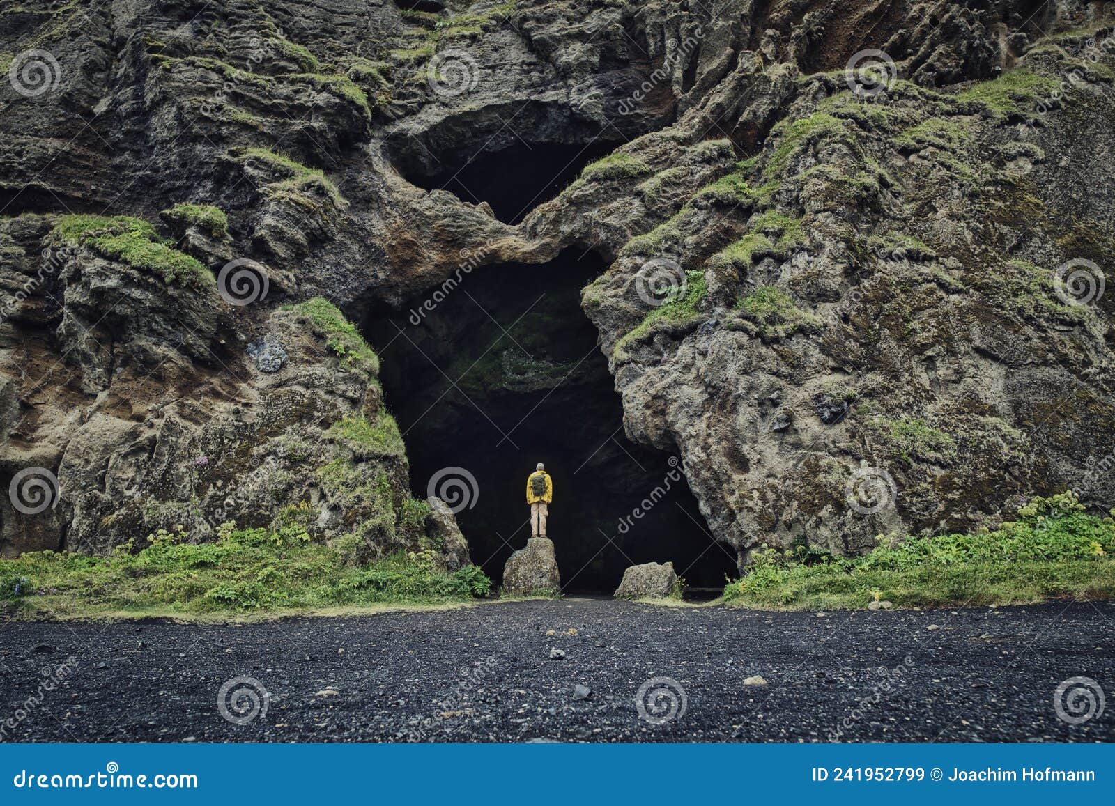 yoda cave at hjorleifshofdi in iceland, guy with yellow raincoat and backpack