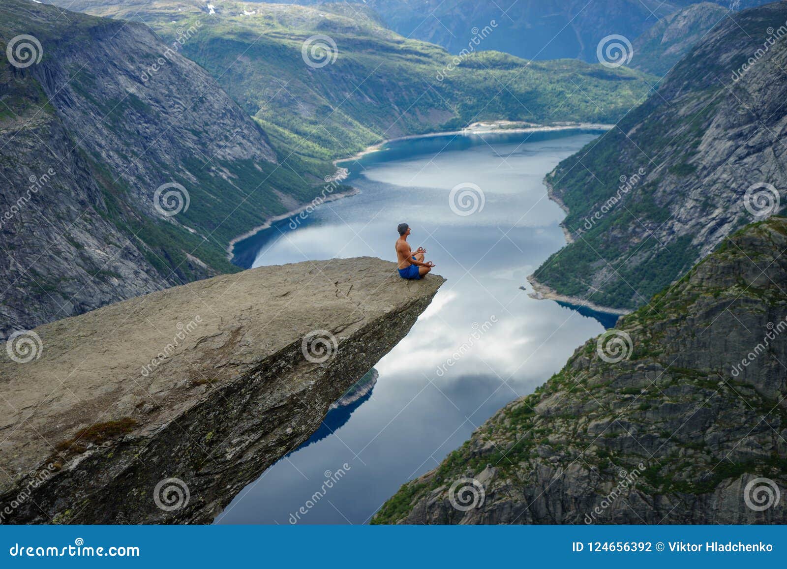 yog is praying on the edge trolltunga. concept of peace, goodness and serenity