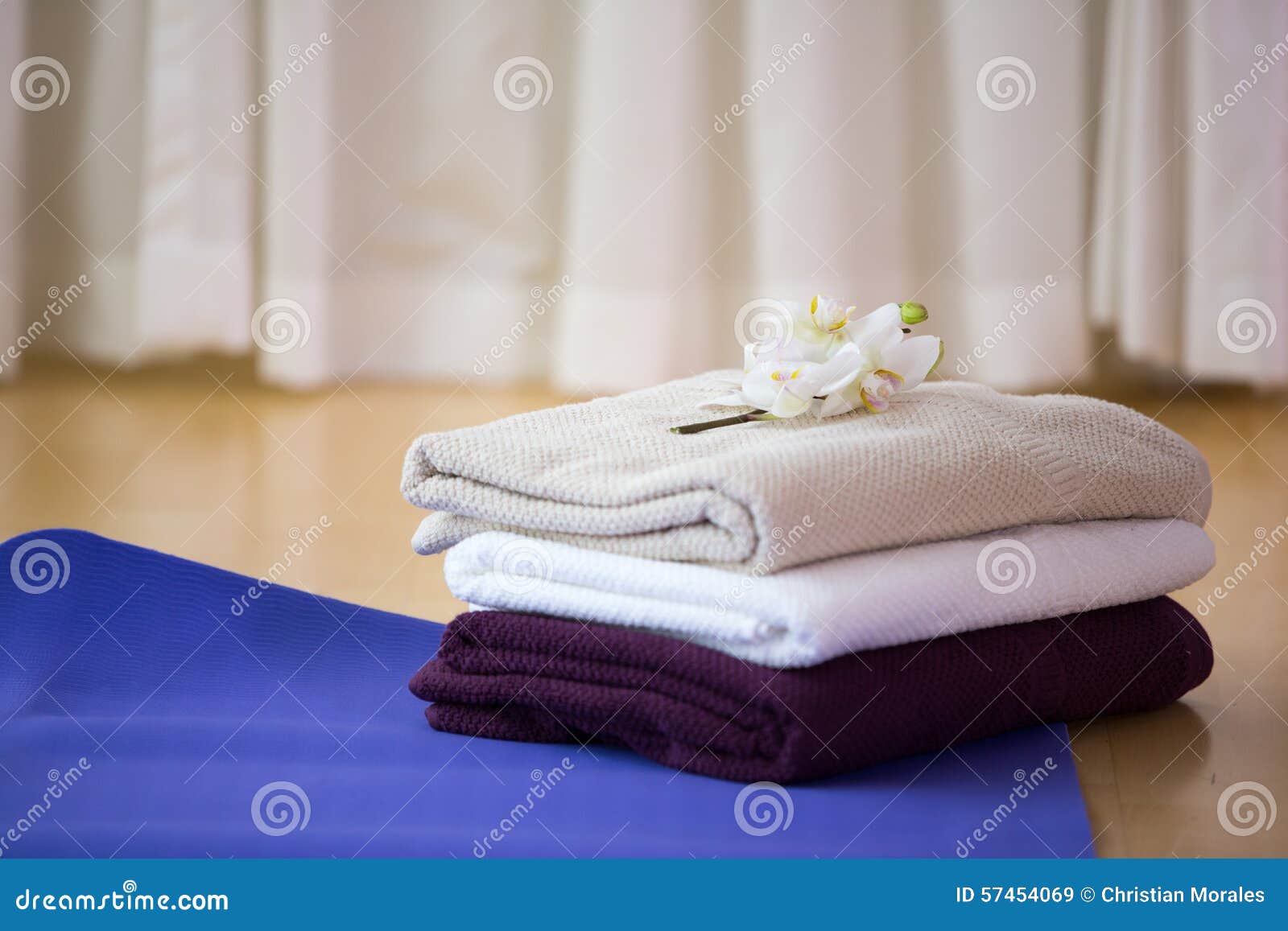 Una stuoia di yoga con gli asciugamani e un fiore sulla cima