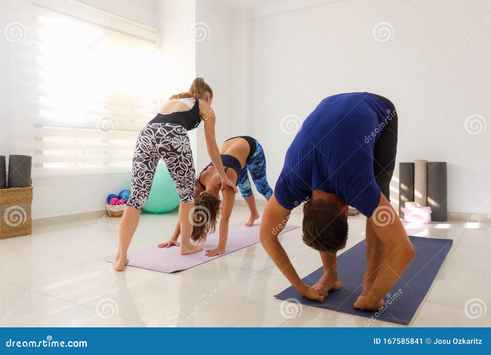 yoga instructor adjusts student in mysore style ashtanga class