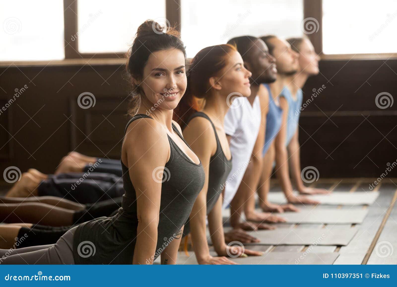 yoga instructor looking at camera doing exercise at group traini