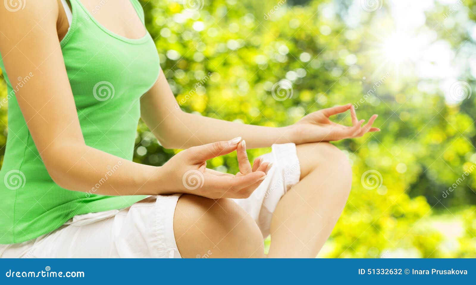 yoga meditation, sitting outdoors in lotus pose, woman meditating hand over green unfocused park