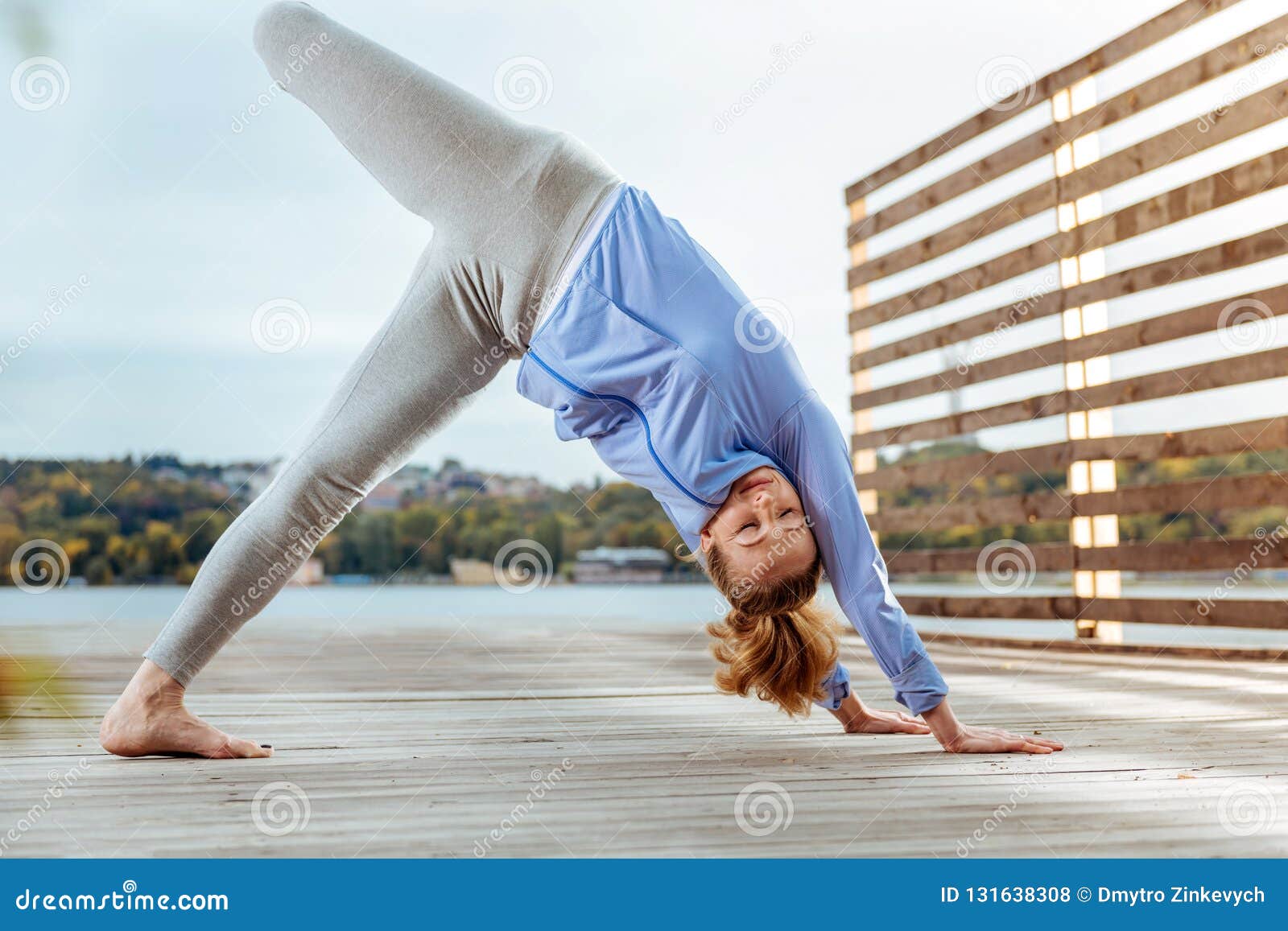 Woman Lifting Leg Up In Downward-Facing Dog Yoga Pose ...