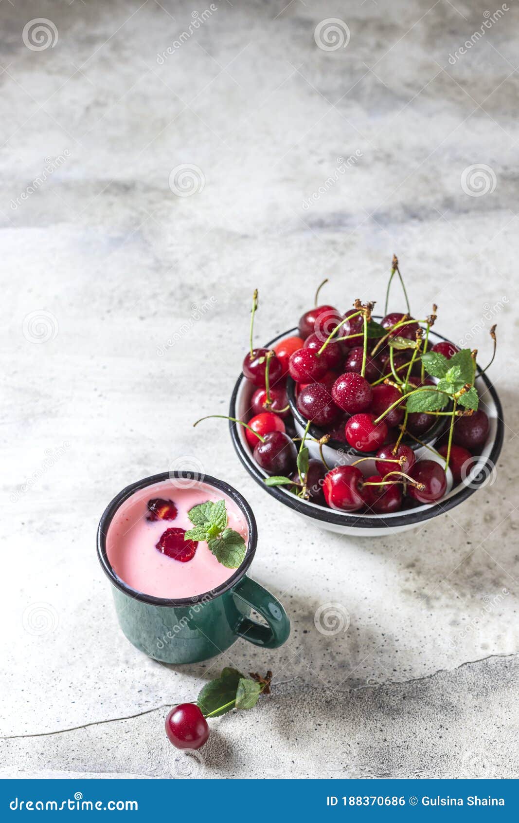 yogurt with cherry, mint and and fresg berries on a light concrete background. summer healthy dessert with berries