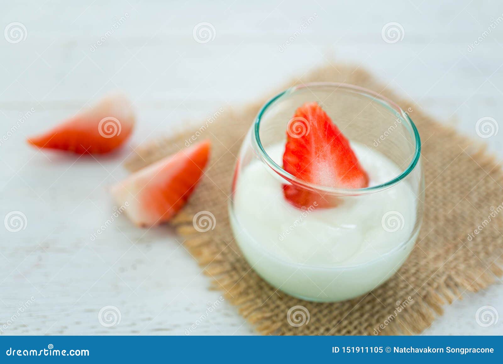 Yogurt originale di sapore con la fragola fresca in vetro trasparente su fondo di legno bianco