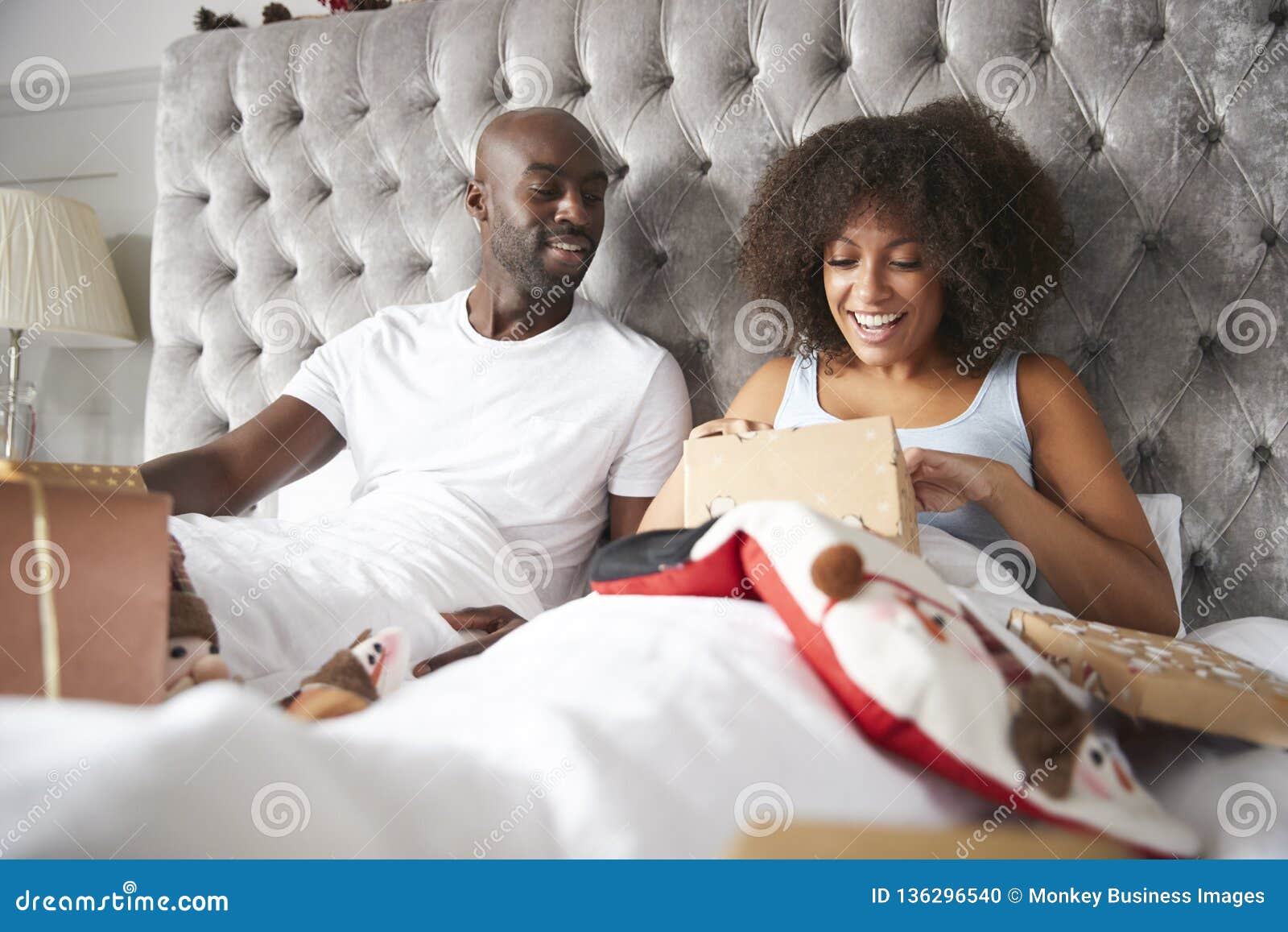 Young Adult Black Couple Opening Gifts in Bed on Christmas Morning, Low ...