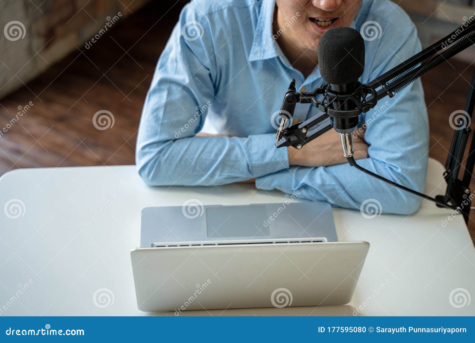 young adult businessman podcasting and recording talk show at home studio with computer laptop on table. the desk is