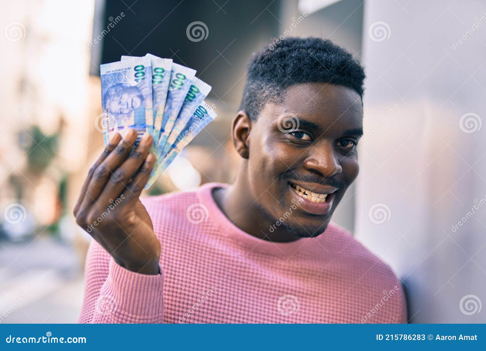 young african american man smiling happy holding south africa rands at the city